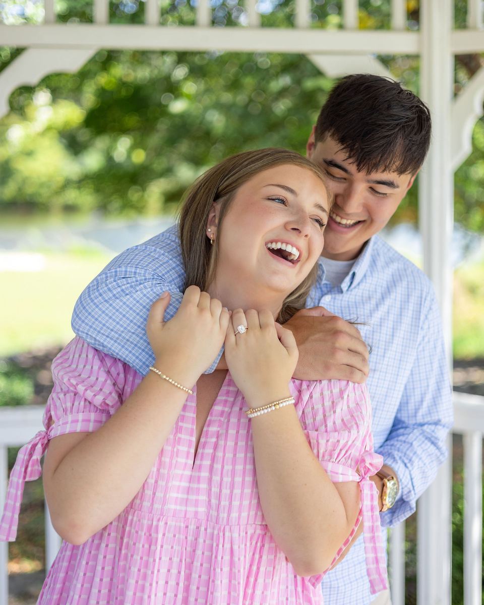 Newly engaged couple laughing, his arms around her shoulders