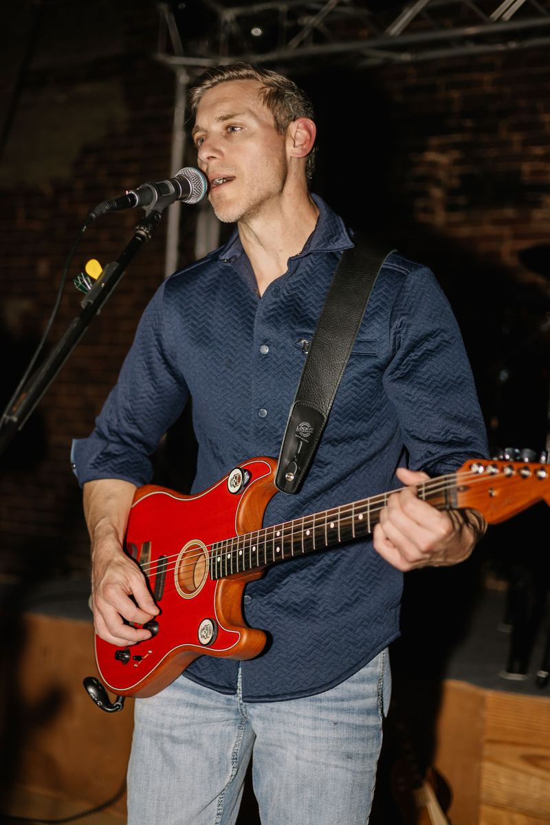 Singer with a red guitar performing on stage