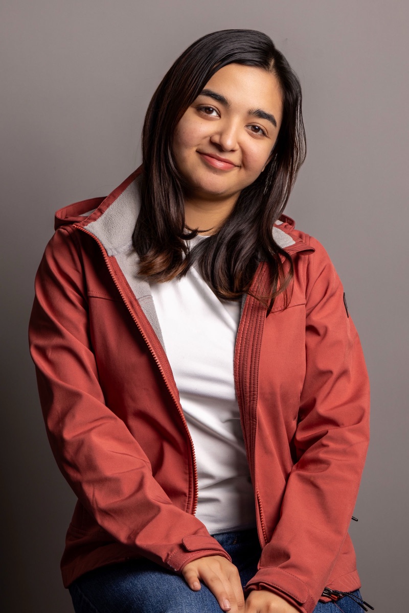 Studio headshot of a woman in a red jacket over a white tee