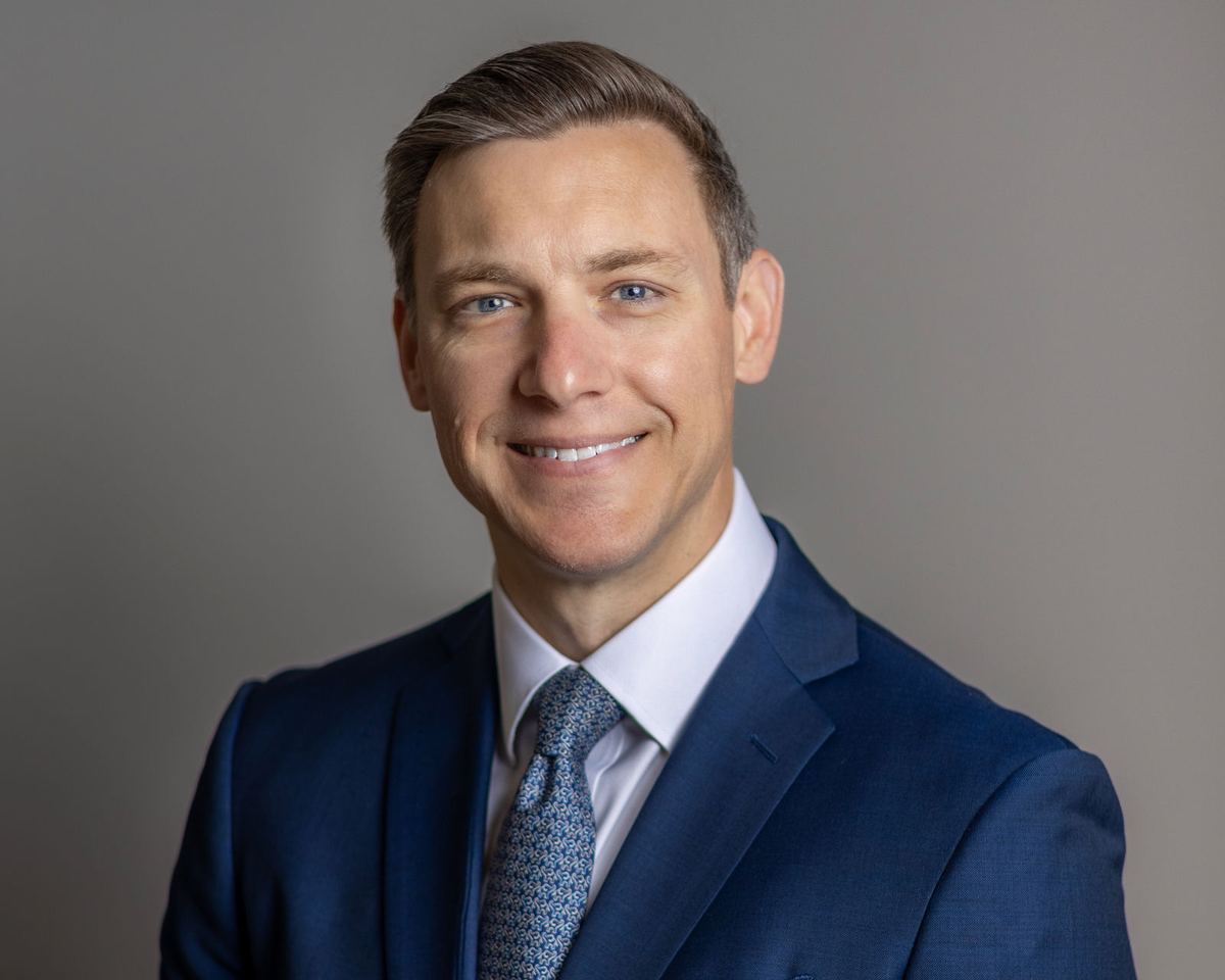 Studio headshot of a man in a navy suit