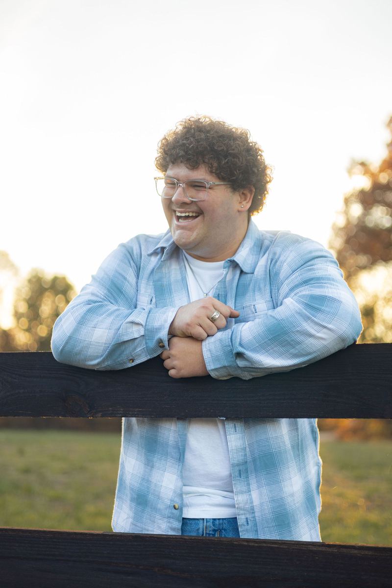 Senior guy laughing on a wooden fence