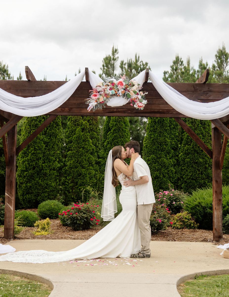 Ceremony: first kiss under a draped pergola