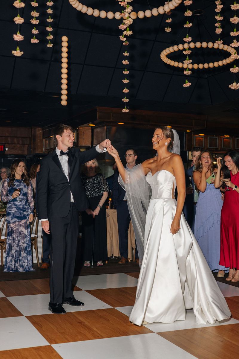 First dance on a checkerboard floor under hanging lights
