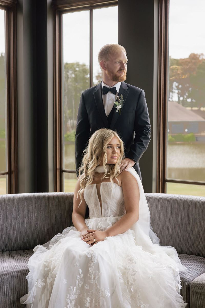 Getting ready: bride seated in window light with the groom behind her