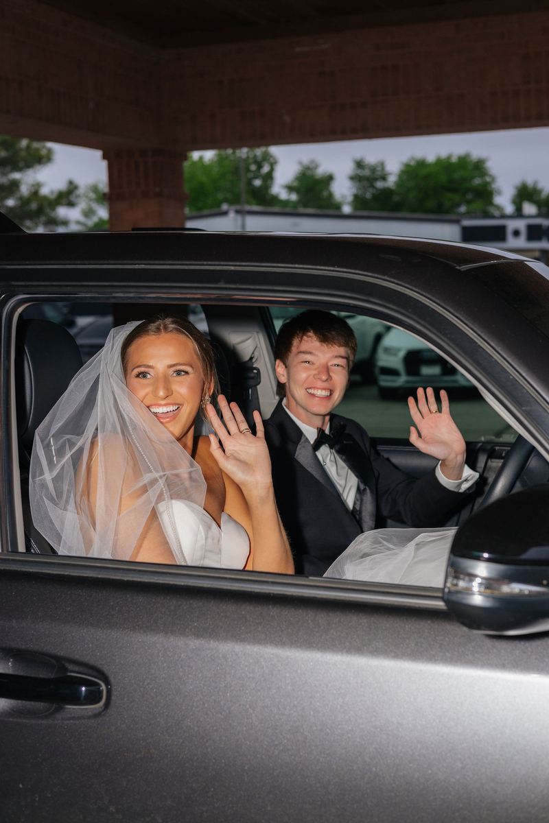 Send-off: bride and groom waving from the car window